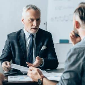 Consultant advises client, sitting on desk.